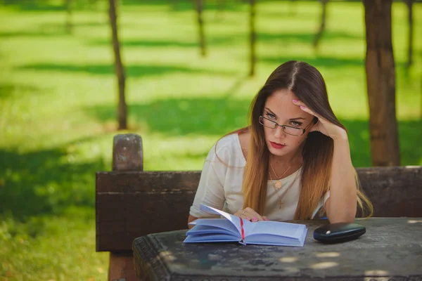 Tyttö kirjan lukeminen puistossa — kuvapankkivalokuva