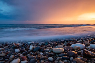 Deniz kıyıları gün batımında taşlarla
