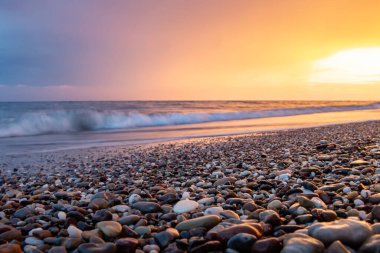 Deniz kıyıları gün batımında taşlarla