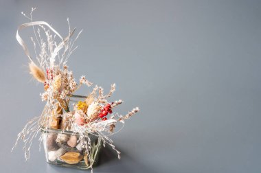 Kurumuş çiçekler gri bir arka planda.