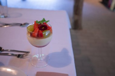 Masanın üzerinde duran cam bardakta meyveli puding.