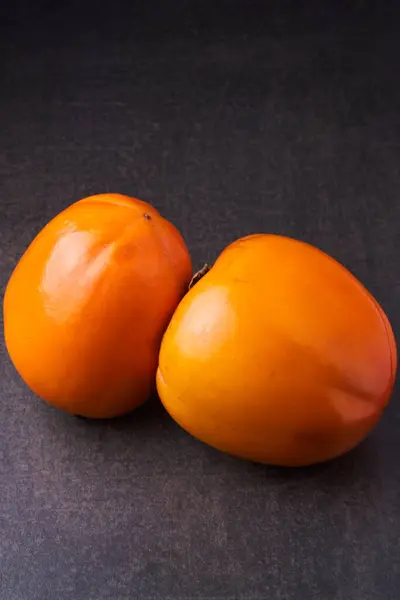 灰色の背景に2つのおいしい熟した柿の柿 — ストック写真