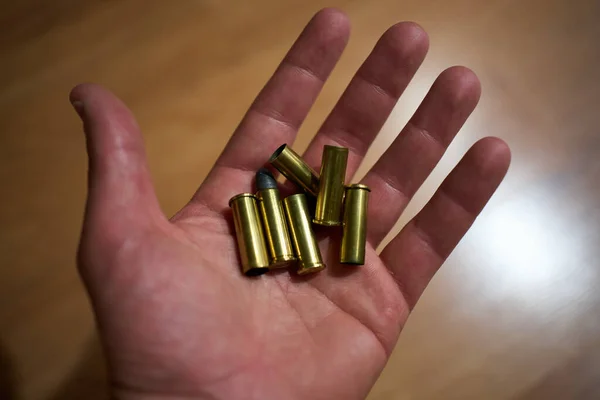 Open hands holding several unexpired revolver bullets and several bullet casings already struck — Stock Photo, Image