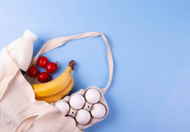 Tablonun tek renk yüzeyinde besin içeren tuval taşıma çantası