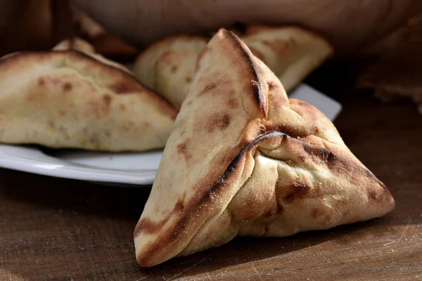 Beyaz bir tabakta et ve soğanla doldurulmuş Arap Pastası ve arka planda kırsal kumaş.