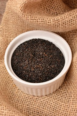 Tahta arka planda bir kasede siyah susam tohumları