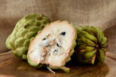 Atımoya meyvesi ahşap masada sepetin içinde ve arka planda kırsal kumaş.