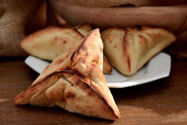 Beyaz bir tabakta et ve soğanla doldurulmuş Arap Pastası ve arka planda kırsal kumaş.