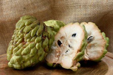 Atımoya meyvesi ahşap masada sepetin içinde ve arka planda kırsal kumaş.