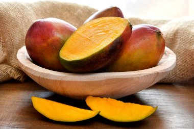 Masadaki ahşap kasede olgunlaşmış mango.