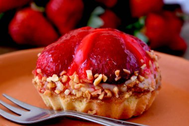 Tahta bir masada seramik bir tabakta mini çilekli turta ve çilekli meyveler.