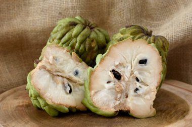 Atımoya meyvesi ahşap masada sepetin içinde ve arka planda kırsal kumaş.