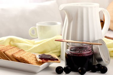 Brezilya üzümleri jaboticaba meyvesi, jöle kavanozunda beyaz bir kavanoz, bardak, tost, spatula, üzümler, beyaz bir tahta üzerinde sarı bez ve beyaz bir arka plan.