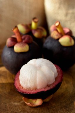 Ahşap bir masada Asyalı Mangosteen meyvesi ve arka planda kırsal kumaş.