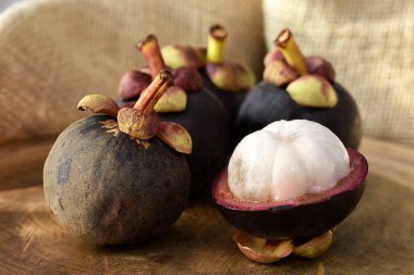 Ahşap bir masada Asyalı Mangosteen meyvesi ve arka planda kırsal kumaş.