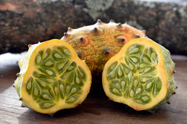 The Kiwano or horned melon african fruit on wooden table and a tree branch at background