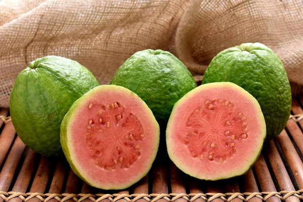 Kırmızı guava ve ahşap bir tencerede dilimler ve kırsal bir kumaş