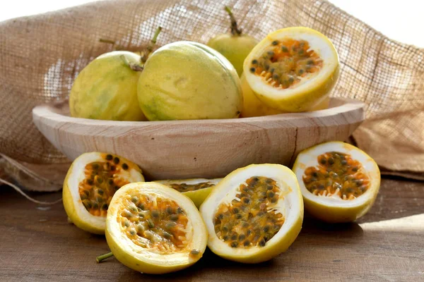 Ahşap bir kasedeki tutku meyvesi ve arka plandaki kırsal kumaş.