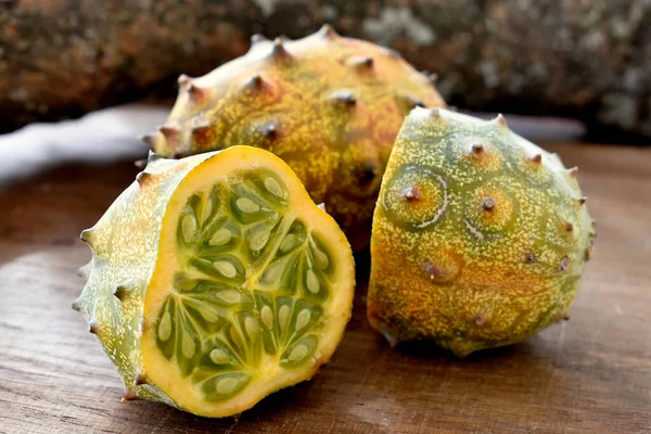 The Kiwano or horned melon african fruit on wooden table and a tree branch at background