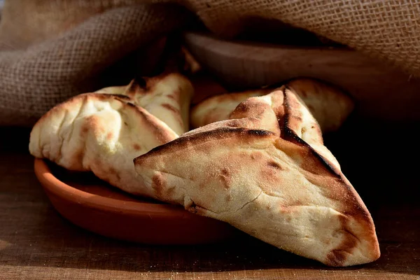 Beyaz bir tabakta et ve soğanla doldurulmuş Arap Pastası ve arka planda kırsal kumaş.