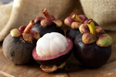 Ahşap bir masada Asyalı Mangosteen meyvesi ve arka planda kırsal kumaş.