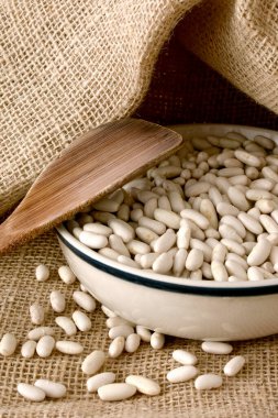 Tahta bir arka planda çuvaldaki beyaz fasulyeler.