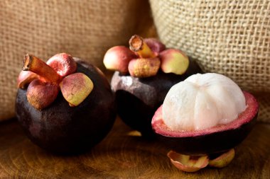 Ahşap bir masada Asyalı Mangosteen meyvesi ve arka planda kırsal kumaş.