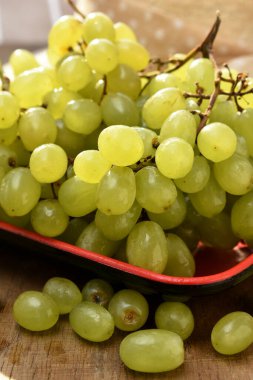 Tahta bir masada, kasede yeşil üzümler