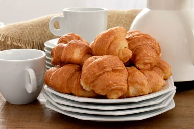 fresh croissants with cup of coffee on table