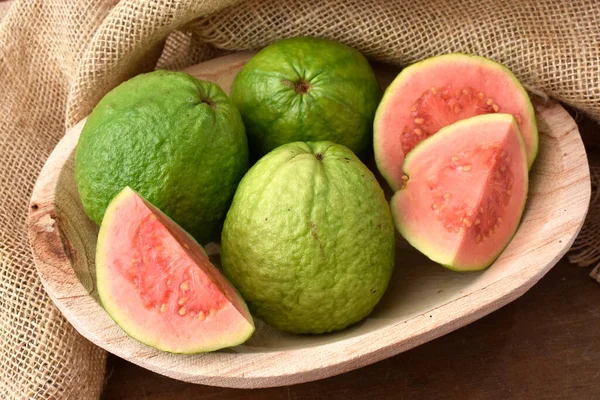 Kırmızı guava ve ahşap bir tencerede dilimler ve kırsal bir kumaş