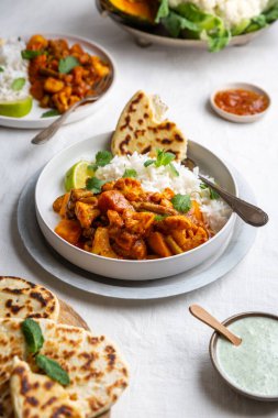 Vejetaryen, vejetaryen Hint körisi, karnabahar ve balkabağı yanında raita, naan ekmeği ve mango turşusu ve beyaz arka planda basmati pilavı.