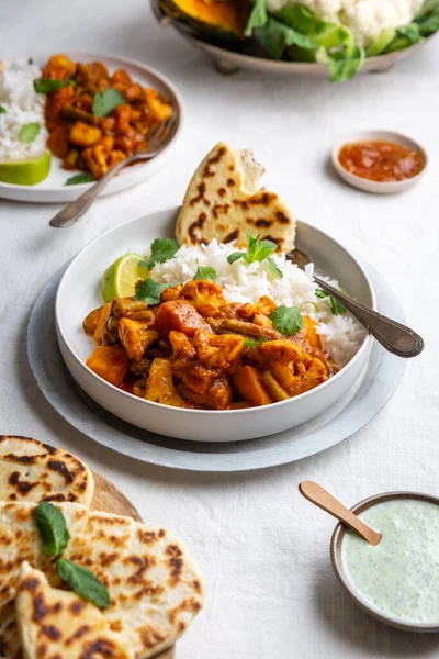 Vejetaryen, vejetaryen Hint körisi, karnabahar ve balkabağı yanında raita, naan ekmeği ve mango turşusu ve beyaz arka planda basmati pilavı.