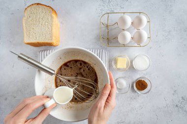 Fransız tostu (ya da wentelteefjes in Dutch) yapmak için yukarıdan beyaz gri arka planda az miktarda malzeme düzleştirilir, kadın tost kabına süt döker, yukarıdan bakıldığında Fransız tostu hazırlanır
