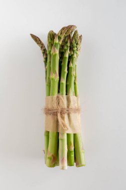 Beyaz bir zemin üzerinde güzel bir çiğ yeşil kuşkonmaz demeti, kopyalama alanı, dikey