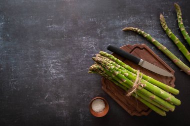 Bir tomar taze taze kuşkonmaz. Siyah arka planda tuz ve bıçakla kesilmiş bir tahta yok.