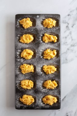 Çiğ kek hamurunu kabartma tenekesinde, beyaz mermer arka planda fotokopi alanı ile tepeden tırnağa görmek