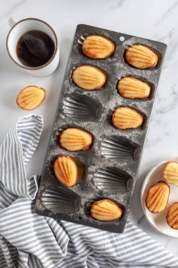 Beyaz mermer arka planda dumanı tüten bir fincan kahveyle yeni pişmiş kurabiyelerin yukarıdan görünüşü