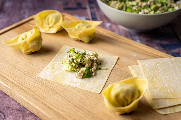 Tahta kesim tahtasında tofu ve brokoli ile vegan wonton hamur tatlısı, yan görüş, sağlıklı beslenme, vejetaryen diyeti.