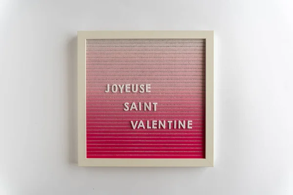 Joyeuse Saint Valentin 'i heceleyen pembe harfli kelimeler (çeviri: Mutlu Sevgililer Günleri), beyaz arka planda, yatay olarak