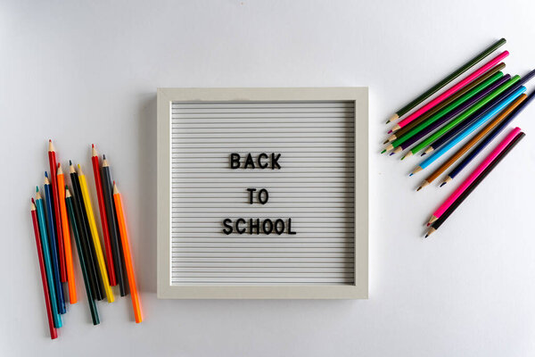 Letterboard with Words That Spell Back To School, with colored pencils on a white background, on a white background, horizontal