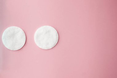 Pamuk pedler, tonik ya da mikiler ile temizleyici su, taze otlar ve pembe arka planda çiçekler, üst manzara. Güzellik, cilt, saç veya vücut bakımı kavramı. Seçici odak.