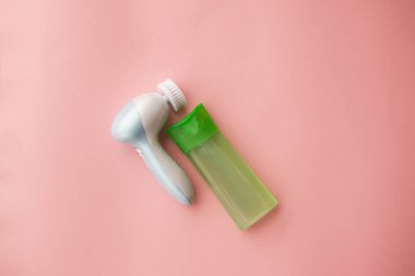 Pembe arka planda yüzü temizlemek için elektrikli fırça temizleyicisi ve jel. Yüz bakımı. Kozmetik alet. Derin cilt temizleme. seçici odak.