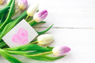 Beyaz ahşap arka planda güzel beyaz ve mor laleler. Bahar. Suluboya kalpli Uluslararası Kadınlar Günü kartı. Sevgililer Günü. Seçici odak.