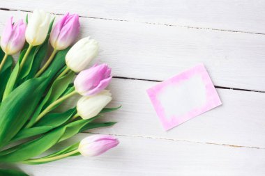 Beyaz ahşap arka planda güzel beyaz ve mor laleler. Bahar. Suluboya kalpli Uluslararası Kadınlar Günü kartı. Sevgililer Günü. Seçici odak.