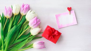 Güzel beyaz ve mor laleler ve beyaz ahşap arka planda kırmızı bir kutuda bir hediye. Bahar. Suluboya kalpli Uluslararası Kadınlar Günü kartı. Sevgililer Günü. Seçici odak.