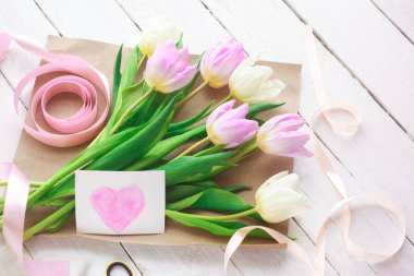 Beyaz ahşap arka planda güzel beyaz ve mor laleler. Bahar. Suluboya kalpli Uluslararası Kadınlar Günü kartı. Sevgililer Günü. Seçici odak.