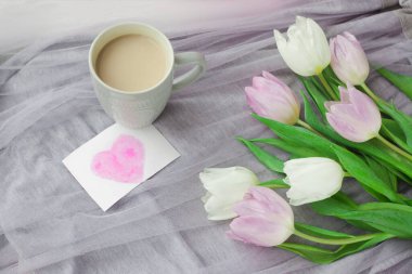 Bir kupa kahveyle bir buket lale ve gri bir bezin üzerinde kırmızı bir kutuda hediye. Uluslararası Kadınlar Günü, Sevgililer Günü, Anneler Günü. Seçici odak