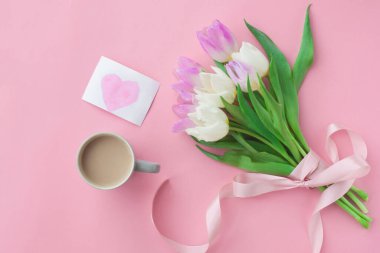 Bir buket lale ve pembe pastel arka planda bir kahve fincanı. Anneler Günü veya Kadınlar Günü 'nde harika bir bahar kahvaltısı. Düz yatıyordu. Üstten bak. Seçici odak