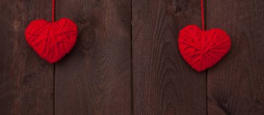 Ahşap arka planda kırmızı yün iplikten yapılmış iki kalp. Sevgililer Günü konsepti.