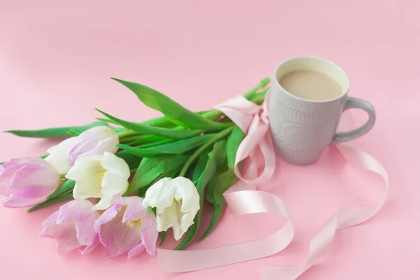 Bouquet of tulips and a coffee cup on a pink pastel background. Wonderful spring breakfast on Mother\'s Day or Women. Flat lay. View top. Selective focus